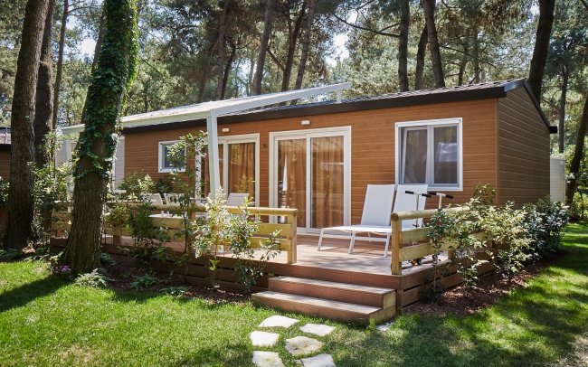 Bungalow di legno con terrazza circondato da alberi.