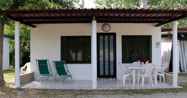 Bungalow con veranda, sedie a sdraio e tavolo.
