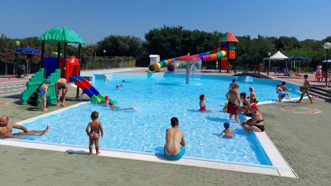 Piscina con scivoli colorati e persone che si divertono.