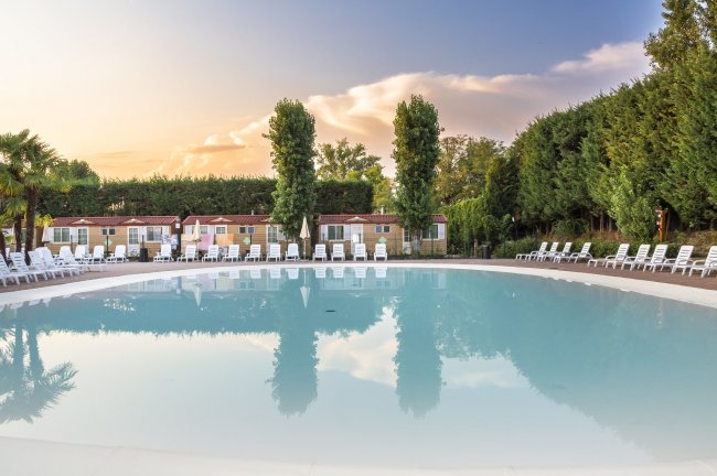 Piscina circolare con lettini vuoti al tramonto.