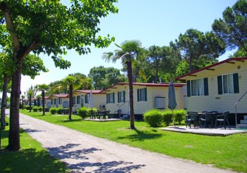 Bungalow allineati tra alberi e prato.